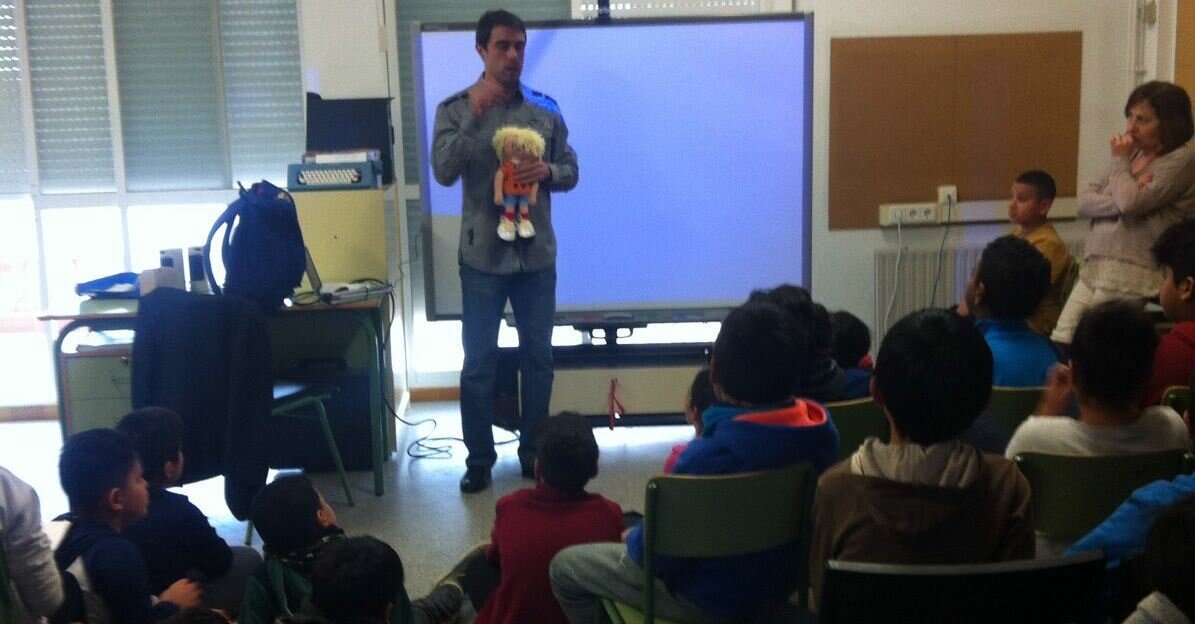 Imagen de Xavi Porras dando una charla a alumnos de primaria con la muñeca Braillina en las manos.ok